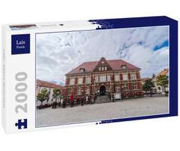  A 2000-piece puzzle depicting a historic town hall building in Calau, Germany. The image shows a traditional German-style building with a red-tiled roof, surrounded by trees and other buildings in a town square setting.