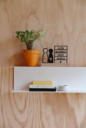 Decorative shelf with potted plant, books, and abstract figurines. Neutral wood tones and minimalist decor.