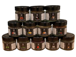 A set of 12 different sea salt varieties from Mallorca, packaged in small glass jars with black lids. The jars feature labels with the product name and information.