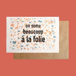 A colorful greeting card with the text "On seme beaucoup a la folie" (We sow a lot madly) against a patterned background.