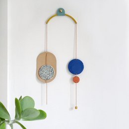 Porcelain wall jewelry in an arc shape, featuring nude and kobalt, or copper and nude color variants. Circular elements with textured patterns create a modern, minimalist design.