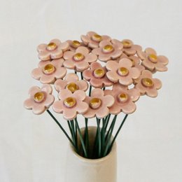 Artificial pink, yellow, and white flowers in a vase. Floral arrangement with round, daisy-like blooms.