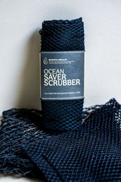 A thick, durable black scrubbing sponge made of recycled materials for cleaning dishes and surfaces in the kitchen.