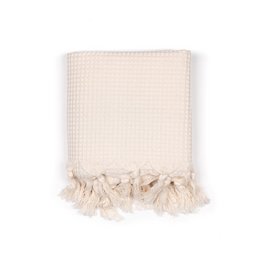 Handwoven ecru waffle piqué towel with tasseled edges, suitable for use as a hammam towel.