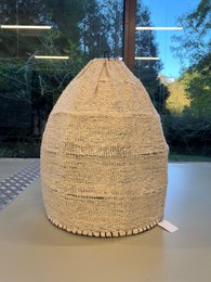 Lamp shade made of woven natural material, cylindrical shape, neutral beige color.